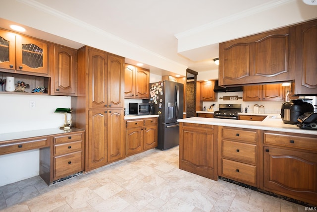 kitchen with extractor fan, appliances with stainless steel finishes, built in desk, and crown molding