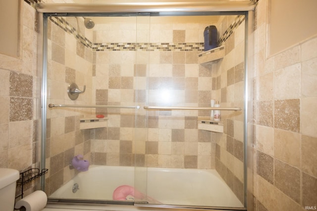 bathroom with bath / shower combo with glass door and toilet