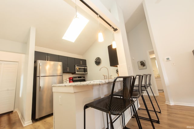 kitchen with a breakfast bar, pendant lighting, a skylight, kitchen peninsula, and stainless steel appliances