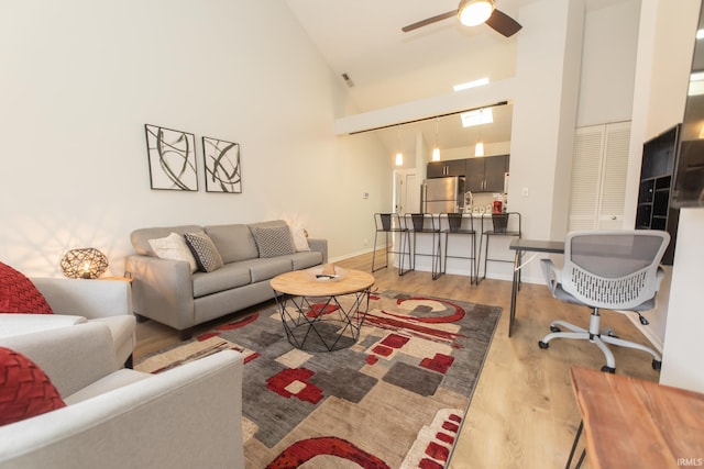 living room featuring ceiling fan, high vaulted ceiling, and light hardwood / wood-style flooring