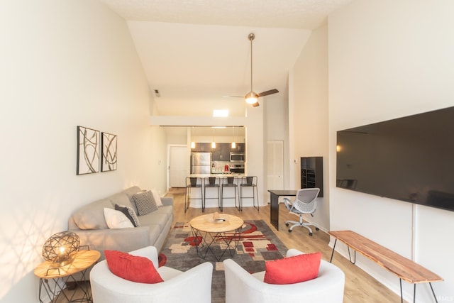 living room featuring high vaulted ceiling, ceiling fan, and light wood-type flooring