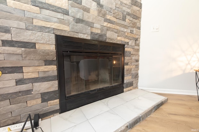 room details with a stone fireplace and wood-type flooring