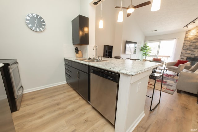 kitchen with sink, a breakfast bar area, kitchen peninsula, stainless steel appliances, and light stone countertops