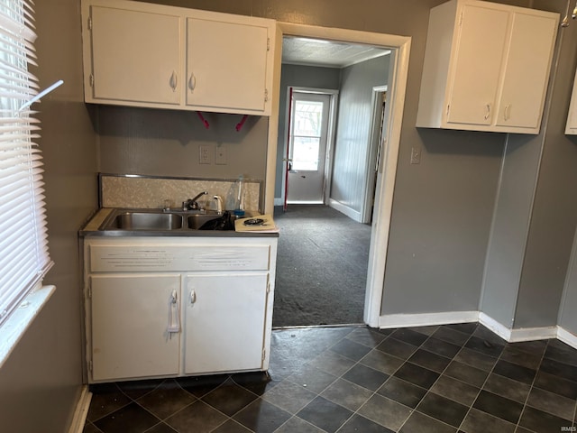 kitchen with dark colored carpet, sink, and white cabinets