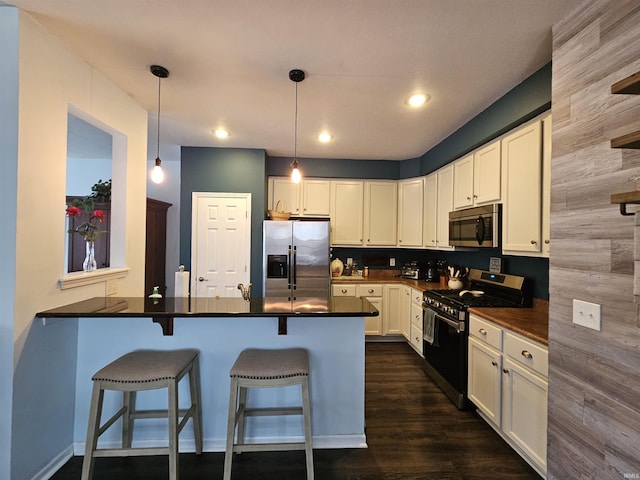 kitchen with a breakfast bar, appliances with stainless steel finishes, hanging light fixtures, white cabinets, and kitchen peninsula