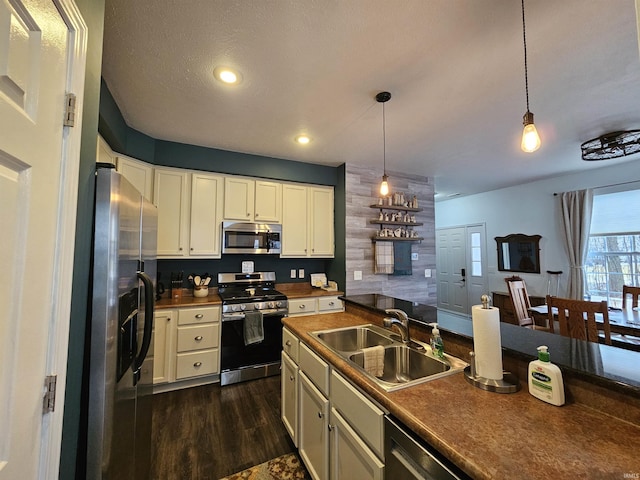 kitchen featuring appliances with stainless steel finishes, sink, dark wood-type flooring, and decorative light fixtures