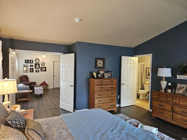 bedroom with lofted ceiling, dark hardwood / wood-style floors, and ensuite bath