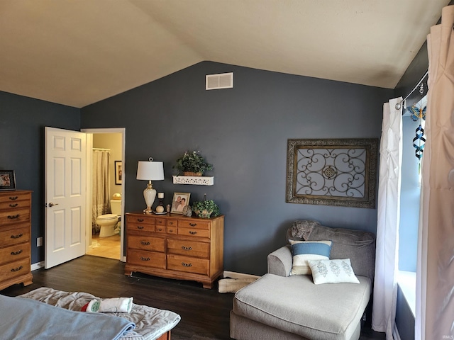 bedroom featuring dark hardwood / wood-style flooring, ensuite bath, and vaulted ceiling