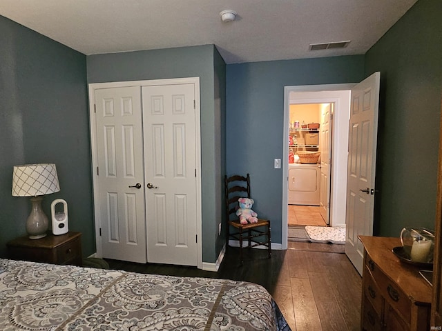 bedroom featuring dark wood-type flooring, independent washer and dryer, and a closet