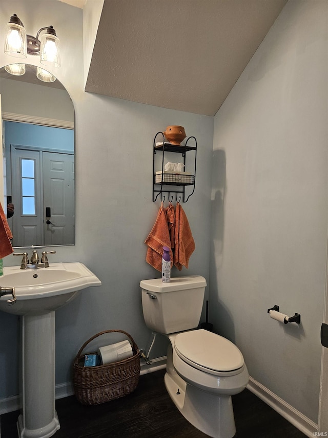 bathroom featuring hardwood / wood-style flooring, lofted ceiling, and toilet