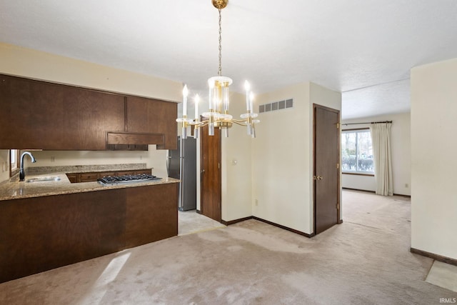 kitchen with appliances with stainless steel finishes, sink, hanging light fixtures, kitchen peninsula, and light carpet