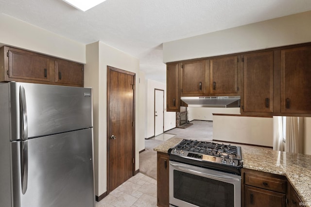 kitchen featuring light stone countertops, stainless steel appliances, and a textured ceiling