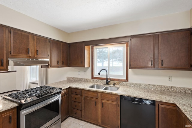 kitchen featuring sink, gas range, light stone counters, dark brown cabinets, and black dishwasher