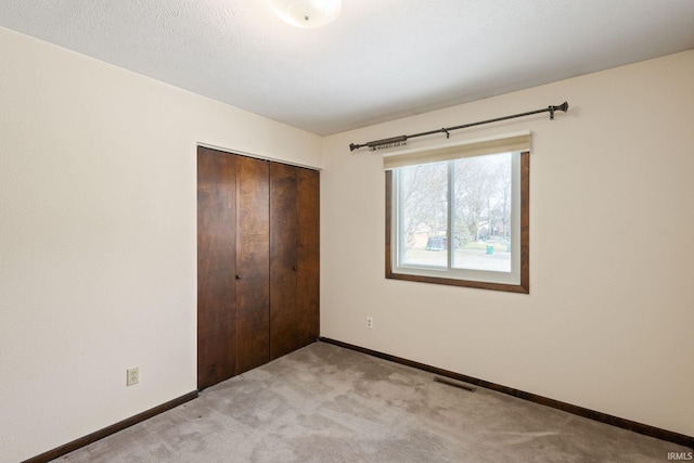 unfurnished bedroom featuring light colored carpet, a closet, and a textured ceiling