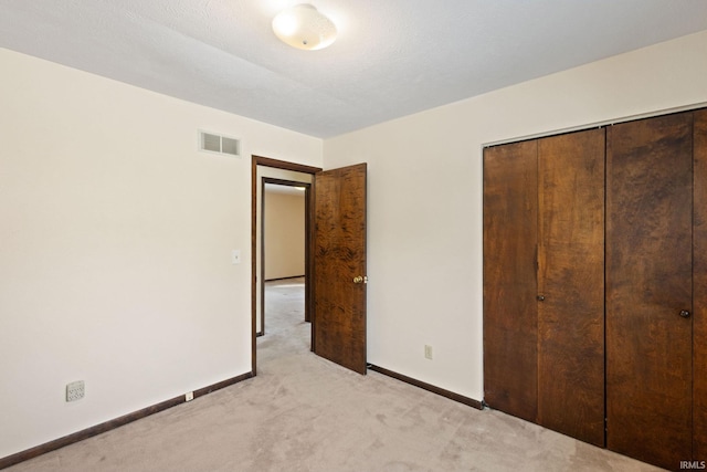 unfurnished bedroom featuring light carpet and a closet