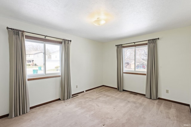 spare room with light colored carpet and a textured ceiling