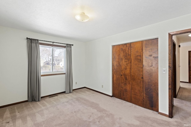 unfurnished bedroom with light colored carpet, a textured ceiling, and a closet