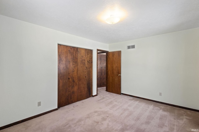 unfurnished bedroom with light colored carpet, a closet, and a textured ceiling