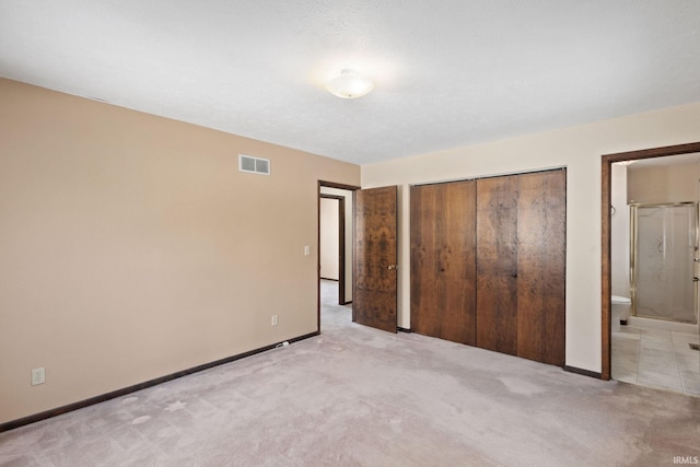 unfurnished bedroom featuring a closet, connected bathroom, and light carpet