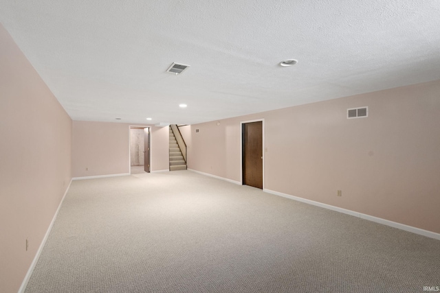 basement featuring light carpet and a textured ceiling