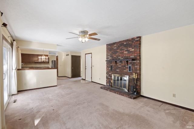 unfurnished living room featuring a fireplace, ceiling fan with notable chandelier, and light carpet