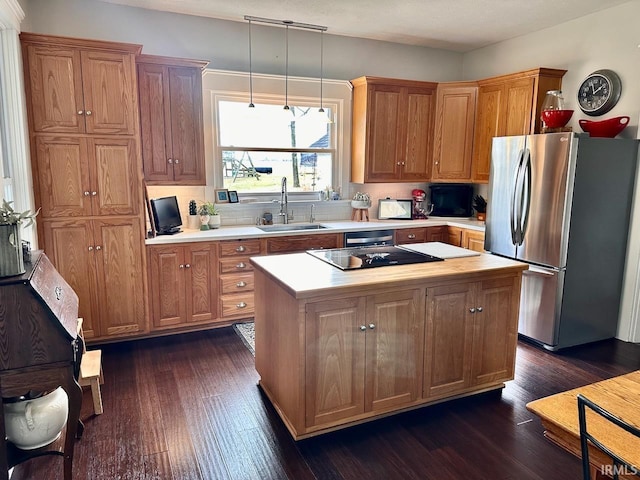 kitchen with pendant lighting, sink, stainless steel fridge, and a kitchen island