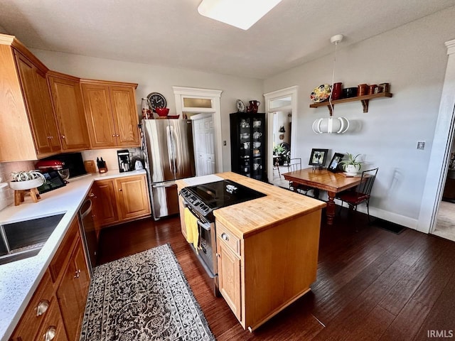 kitchen featuring dark hardwood / wood-style flooring, appliances with stainless steel finishes, a center island, and wood counters