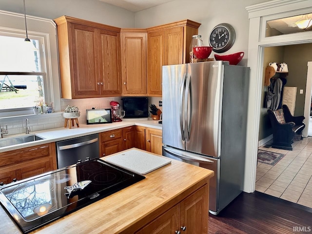 kitchen featuring tasteful backsplash, sink, hanging light fixtures, dark tile patterned floors, and stainless steel appliances