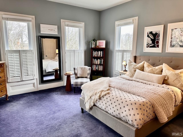 bedroom with multiple windows and dark carpet