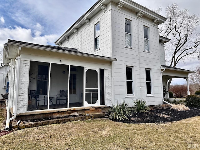 back of house featuring a lawn and a sunroom