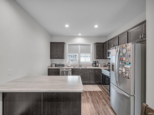 kitchen featuring sink, hardwood / wood-style flooring, dark brown cabinets, and appliances with stainless steel finishes