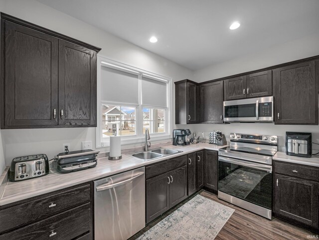 kitchen with sink, dark brown cabinets, dark wood-type flooring, and stainless steel appliances