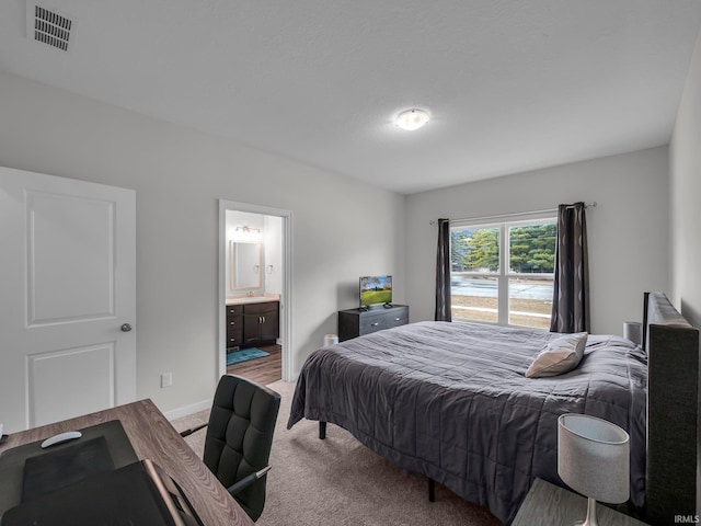 bedroom featuring light colored carpet and ensuite bathroom