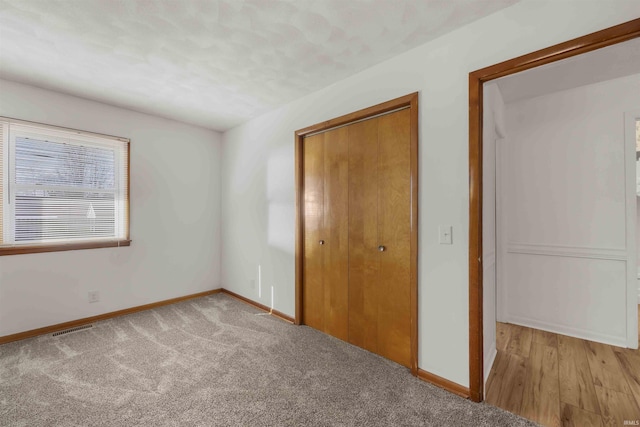 unfurnished bedroom with light carpet and a closet