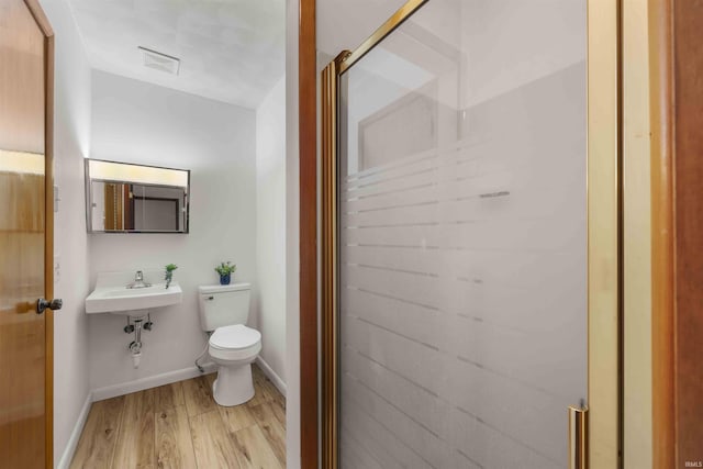 bathroom with walk in shower, wood-type flooring, toilet, and sink