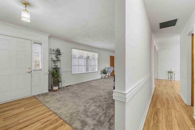 entryway with crown molding and light hardwood / wood-style floors