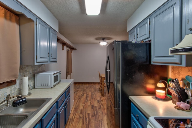 kitchen featuring sink, dark wood-type flooring, a textured ceiling, and blue cabinetry