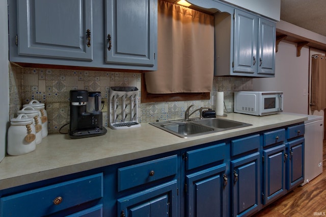 kitchen featuring dark hardwood / wood-style flooring, sink, backsplash, and blue cabinets