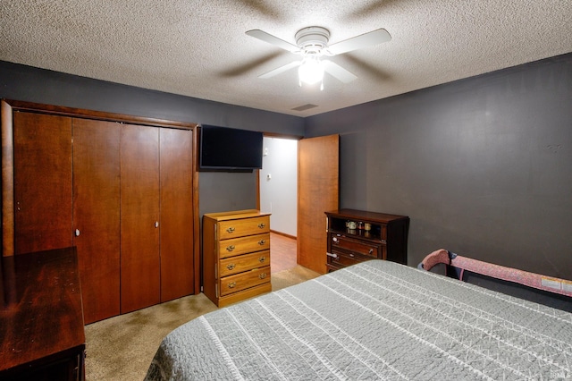 carpeted bedroom with ceiling fan, a closet, and a textured ceiling