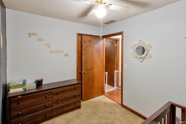 carpeted bedroom featuring ceiling fan and a textured ceiling