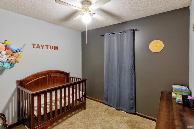 carpeted bedroom with ceiling fan, a textured ceiling, and a crib