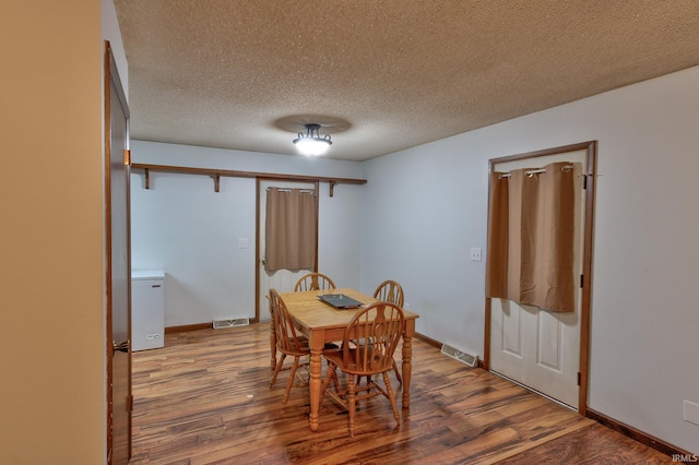 dining room featuring wood-type flooring and a textured ceiling