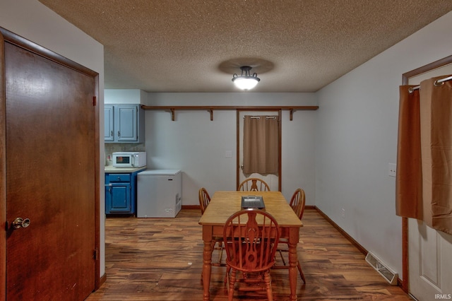 dining space featuring dark wood-type flooring and a textured ceiling