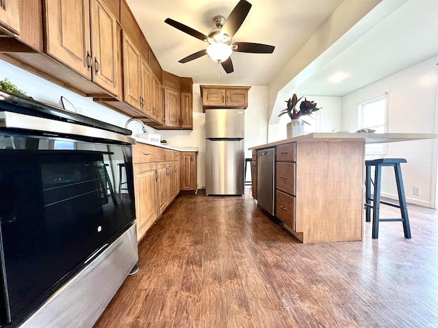 kitchen featuring a kitchen bar, a kitchen island, dark hardwood / wood-style floors, and appliances with stainless steel finishes