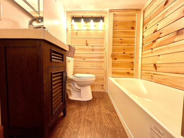 bathroom with toilet, a tub, hardwood / wood-style floors, and wood walls