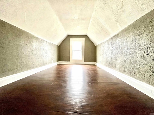 bonus room featuring dark hardwood / wood-style floors, vaulted ceiling, and a textured ceiling