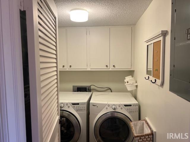 laundry room featuring cabinets, electric panel, separate washer and dryer, and a textured ceiling