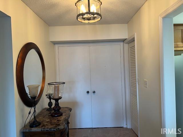 carpeted entrance foyer with a textured ceiling