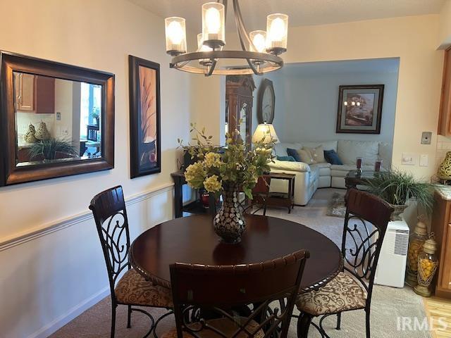 carpeted dining area with an inviting chandelier