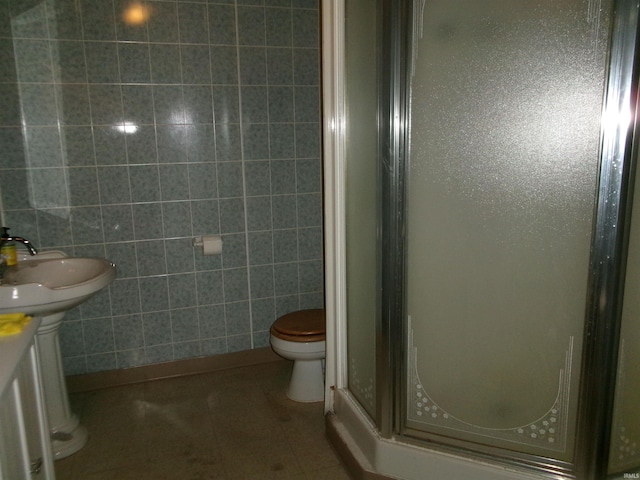 bathroom with toilet, an enclosed shower, sink, tile walls, and tile patterned flooring